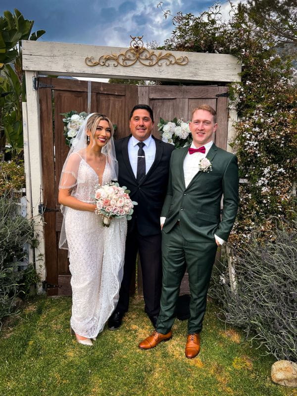 Gabriel Hernandez wedding officiant posing with newlyweds after backyard garden ceremony in Southern California